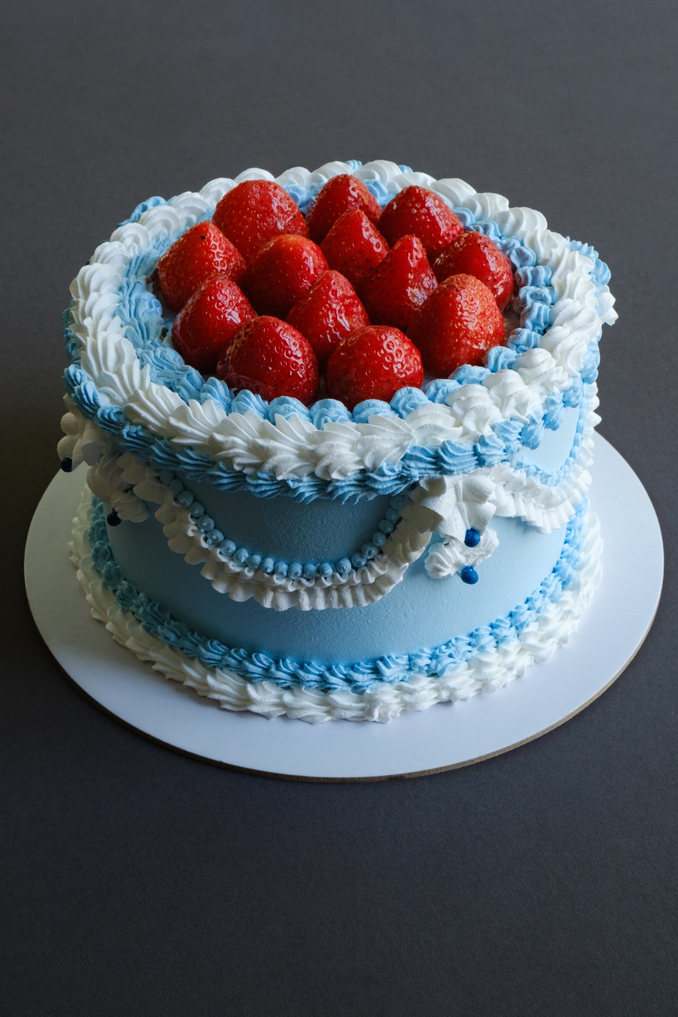 A blue and white vintage piped cake topped with fresh strawberries